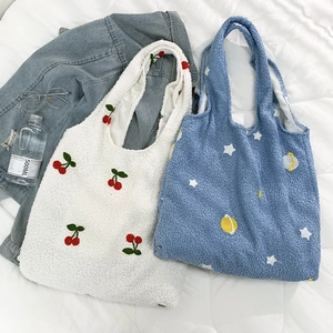 Close-up of plush teddy fleece tote bags with cherry and star embroidery details