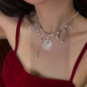Detail of shell pearl tassel necklace with silver chain on model in red velvet dress
