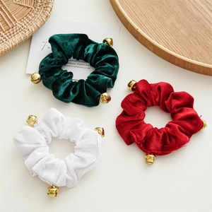 Close-up of velvet hair scrunchies in red, green and white with small gold bells