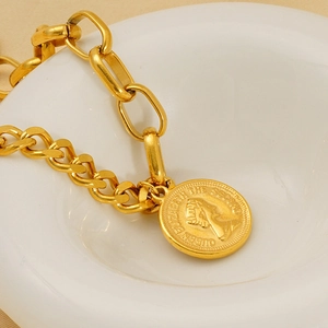 Detailed close-up of a vintage gold queen portrait pendant on a mixed link chain bracelet