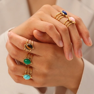 Close-up of vintage multi-layer gold rings featuring turquoise and oval gemstones on hands