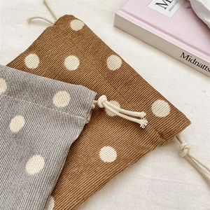 Close-up of corduroy drawstring pouches with polka dot patterns in brown and grey