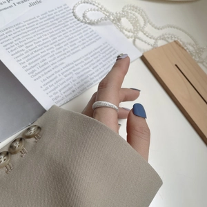 Detail of a sparkling frosted S925 sterling silver ring worn on a finger with book background