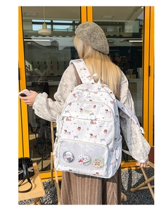 Detail of white backpack with colorful dog patterns and a clear mesh pocket with badges