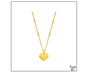Macro shot of gold heart pendant with Love engraving and delicate chain texture