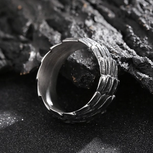 Macro shot of silver punk dragon scale texture ring on dark rugged volcanic stone