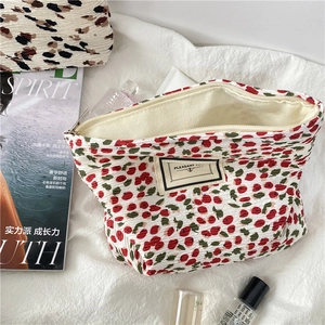Detailed view of floral pleated chiffon makeup bag with red and green flower patterns