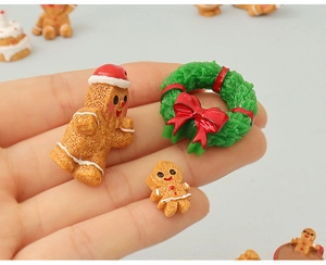 Detailed close-up of miniature gingerbread men and Christmas wreath held in hand