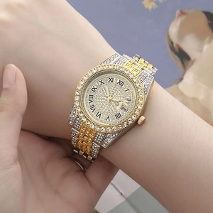 Close-up of gold and silver steel watch with crystal-encrusted bezel and Roman dial