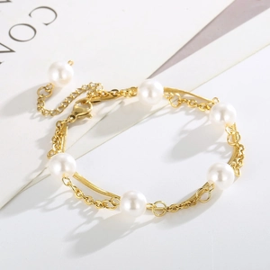 Close-up of golden double-layer chain bracelet featuring white pearls in retro French style