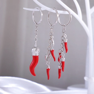 Close-up of red chili keychains with silver crown charms on a white display branch