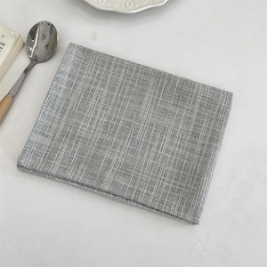 Close-up of gray checkered linen placemat with wooden spoon on a white surface