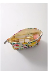 Top view of open canvas floral makeup bag with cosmetics and secure zipper detail