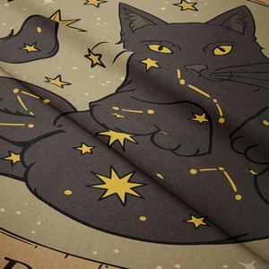 Close-up of soft bohemian fabric featuring a black cat with stars and constellation patterns