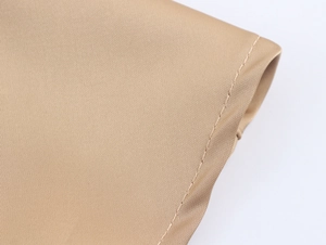 Macro shot of khaki sequin fabric texture with double needle stitching on the garment hem