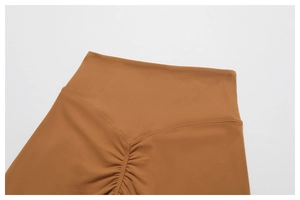 Macro detail of high-waisted caramel yoga pants with V-shaped stitching and scrunch butt