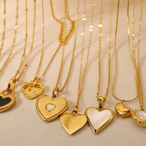 Detailed view of assorted gold heart necklaces with pearl shell and enamel inlays