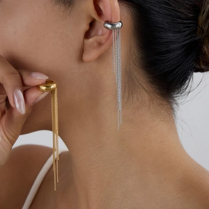 Detail of gold and silver tassel ear bone clips with elegant polished metal chains