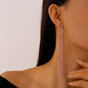 Close-up of pink crystal geometric Greek key drop earrings worn by a model