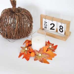 Autumn candle ring with orange maple leaves, mini pumpkins, and pearls around glass candle