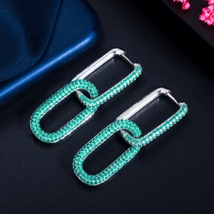 Close-up of silver-plated chain link earrings featuring micro-paved green zircon stones