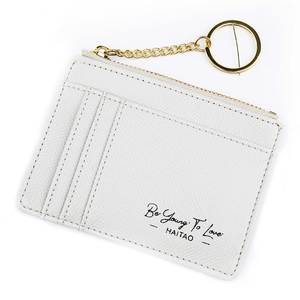 White textured leather card holder with zipper and golden keychain featuring script text