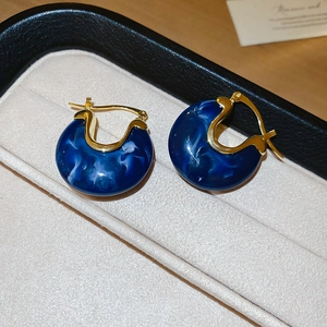 Gros plan de boucles d'oreilles en résine marbrée bleu foncé avec détails dorés vintage
