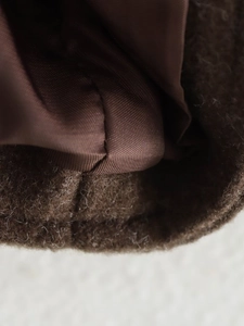 Dettaglio di cuciture su tessuto di lana marrone e fodera setosa di un cappotto moda