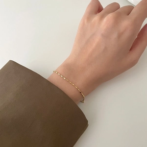 Minimalist gold square link chain bracelet for women on model wrist with brown suit sleeve