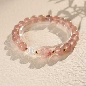 Detailed macro view of pink strawberry quartz bracelet with gold beads and skull charm