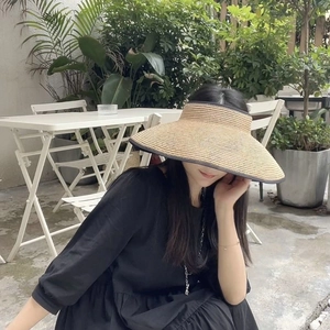 Detailed view of the wide-brimmed straw sun hat with black ribbon edge trim