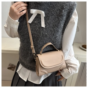 Beige crossbody square bag with curved stitching shown on model for size perspective