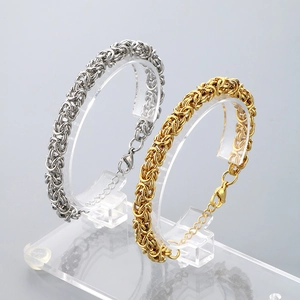 Close-up of Byzantine weave stainless steel dragon bone bracelets in gold and silver
