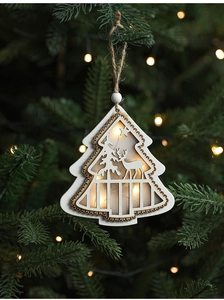 Close-up of lighted wooden star ornament with elk silhouette hanging on Christmas tree