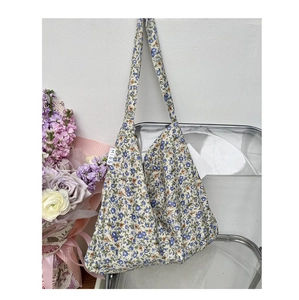 Detail of blue floral canvas tote bag featuring a white Miss woven label on the side