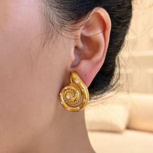 Macro detail of golden spiral shell earrings with shimmering white zircon crystals