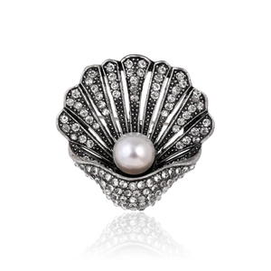 Macro shot of silver scallop brooch featuring sparkling rhinestones and a large center pearl