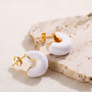 Orecchini minimalisti a forma di C placcati oro con smalto bianco su sfondo di pietra