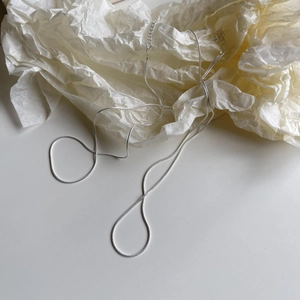 Detailed view of 925 sterling silver snake chain necklace on textured beige paper