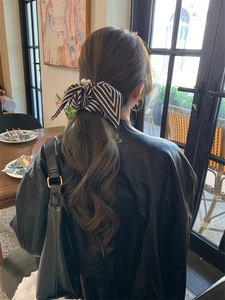 Rear view of model wearing a black and white striped bow hair scrunchie with pearl details