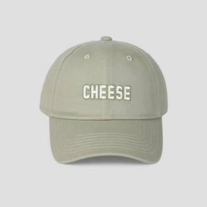 Detailansicht einer salbeigrünen Baseballkappe mit weißer CHEESE-Buchstabenstickerei