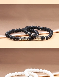 Detail of owl charm and floral tube beads on black volcanic stone beaded bracelet