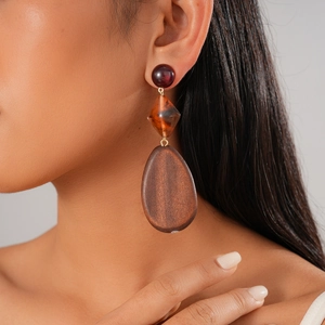 Close-up of bohemian earrings with red resin and dark wood drop pendants on model