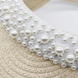 Close-up detail of a summer straw sun visor hat adorned with elegant white pearls.