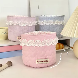 Close-up of three quilted fabric storage baskets with lace trim in pastel colors