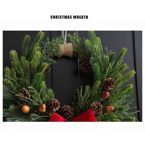 Close-up of Christmas wreath with pine cones, needles, and a red bow on black door