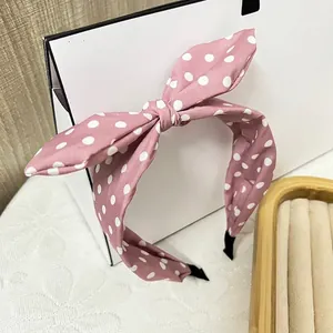 Detail eines rosa gepunkteten Haarreifs mit Hasenohren-Schleife auf Holztablett