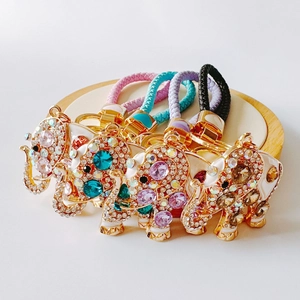 Colorful elephant keychains with rhinestones and braided leather straps on wood base