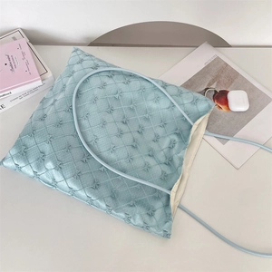 Detailed macro view of light blue quilted tote bag with lace bow accents and soft texture