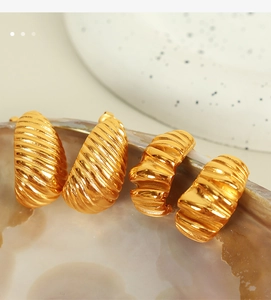 Macro detail of gold-plated twisted earrings with unique spiral texture on a shell